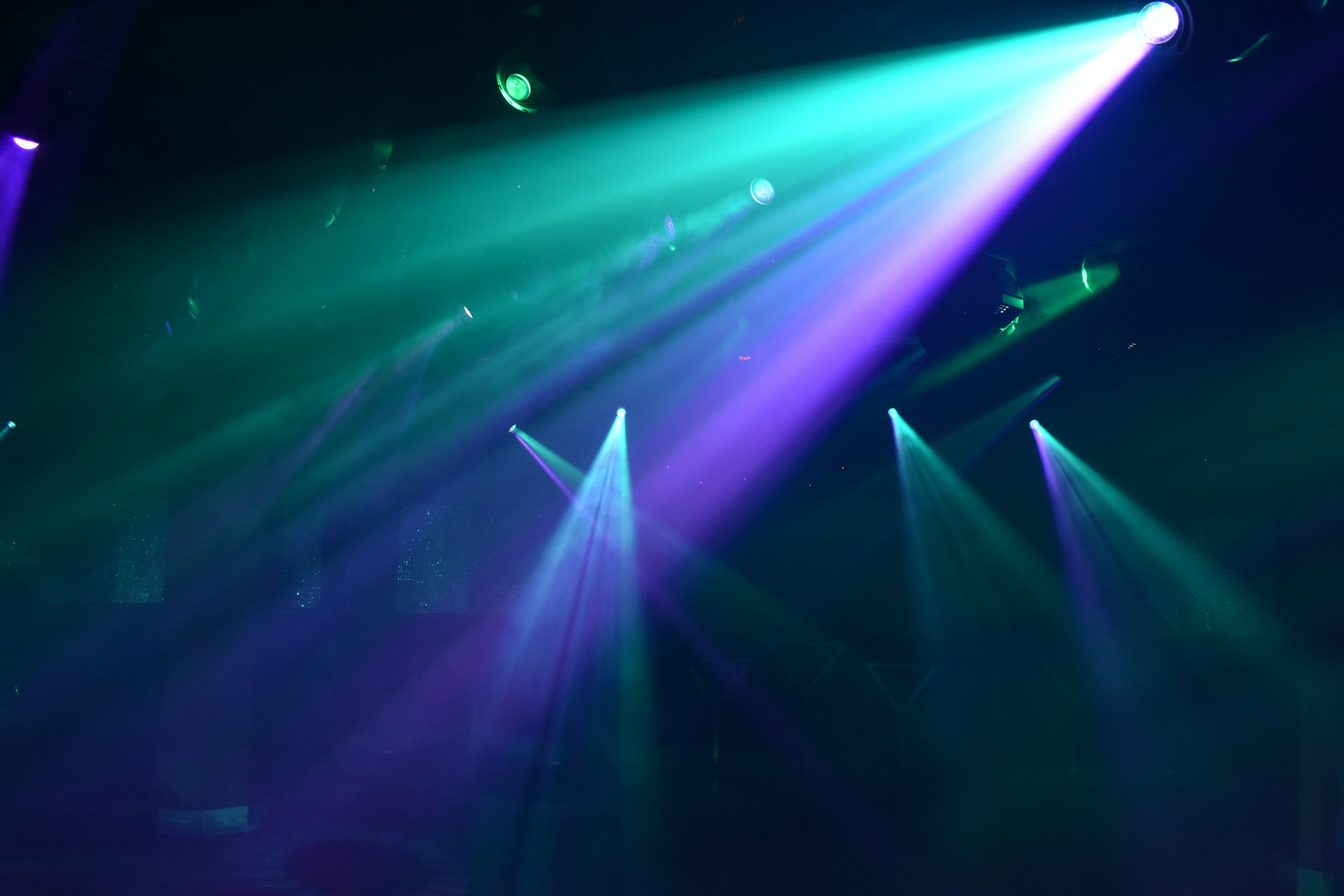 Teal and violet spotlights cutting through a haze of coloured light